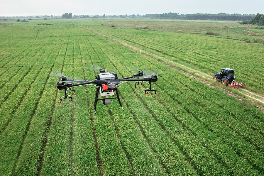 A drone flies over a green field with a tractor